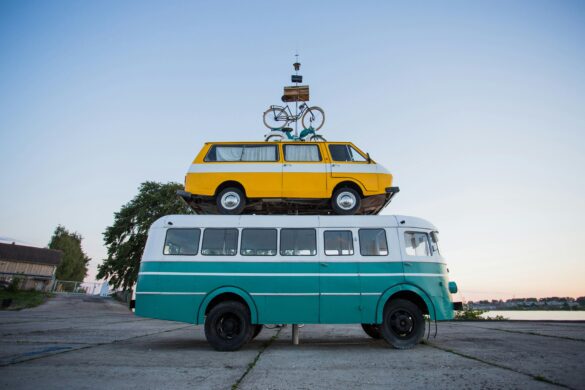 Creative outdoor sculpture featuring a van stacked on a bus with a bicycle on top.